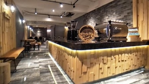 A modern bar area with a wooden counter, marble flooring, and a brick wall. - West.inn48 - Self Check-In Hotel (Taipei)