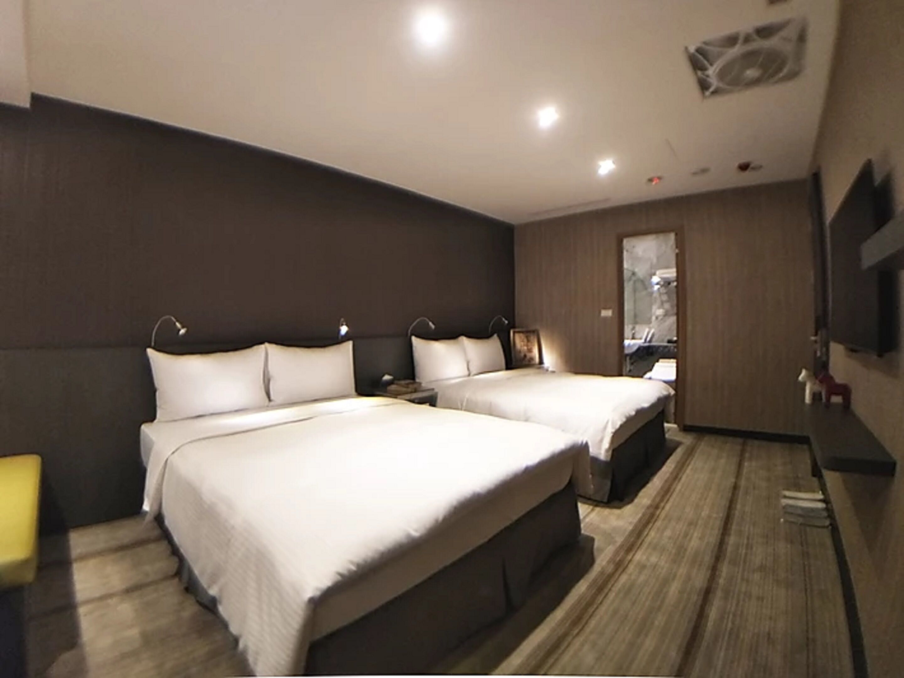 Habitación de hotel con dos camas, un televisor de pantalla plana, una mesita pequeña y un espejo.