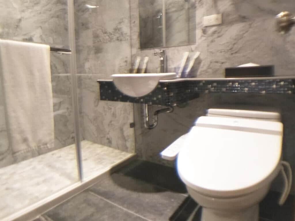 Un bagno con box doccia in vetro, un lavandino bianco e un water.