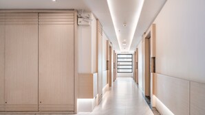 A modern hallway with a wooden wardrobe, recessed lighting, and a marble floor. - Samyan Serene Hotel (Bangkok)