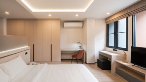A modern hotel room with a large bed, a desk with a chair, a television, and a wardrobe. - Samyan Serene Hotel (Bangkok)