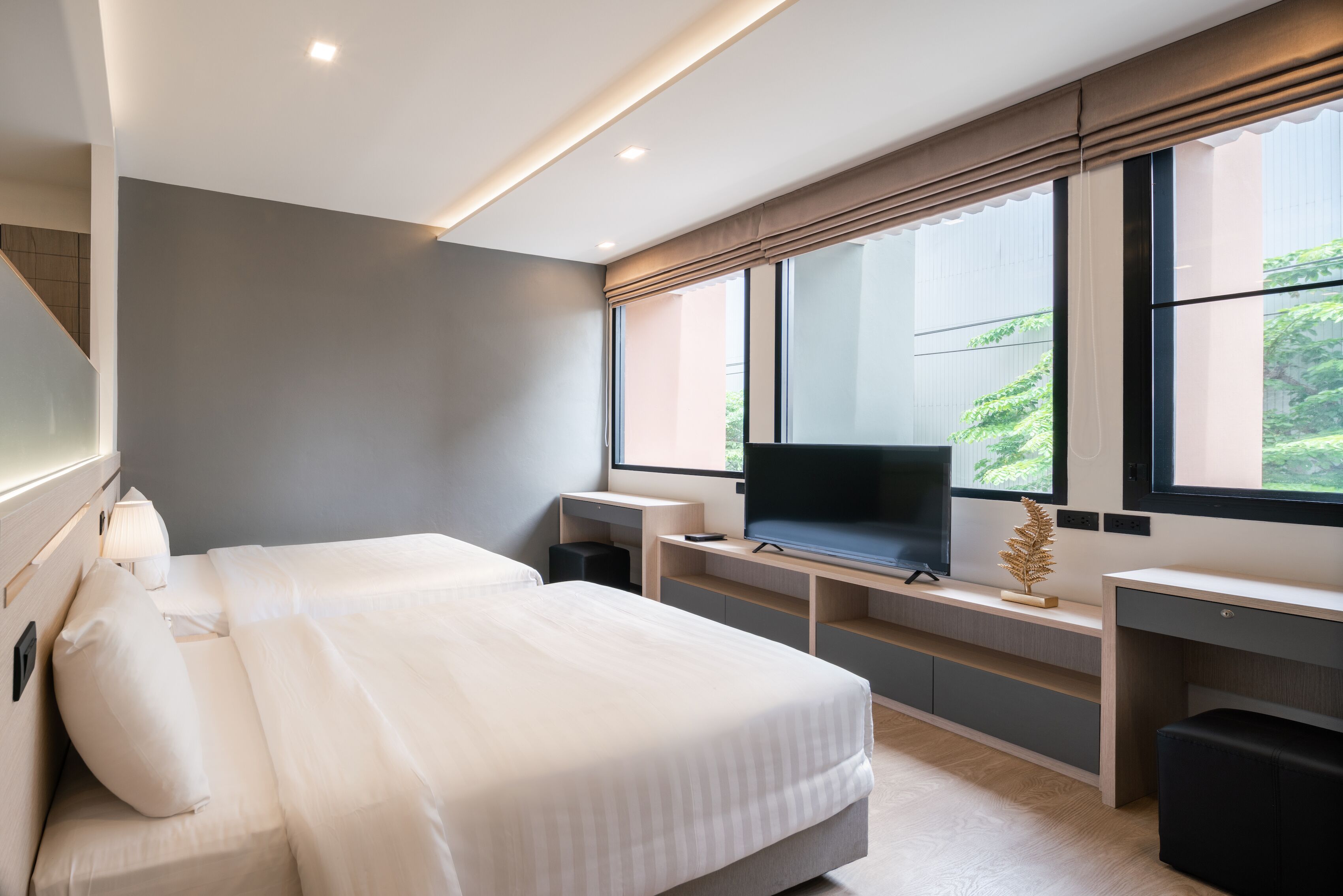 A modern bedroom with a large bed, a desk, and a TV.