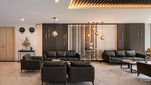 A modern living room with leather sofas, a coffee table, and a decorative wall with clocks and plants. - Samyan Serene Hotel (Bangkok)