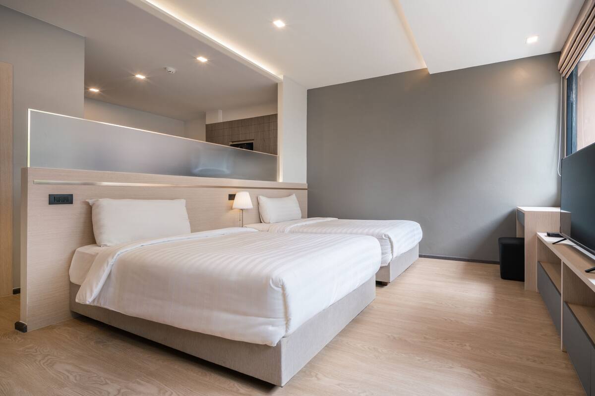 A modern hotel room with a large bed, a TV, and a mirror.