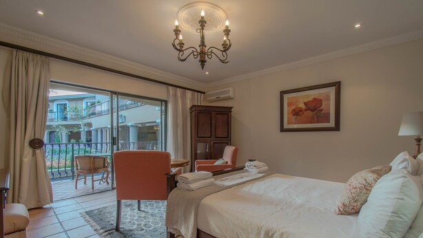 Ein Hotelzimmer mit Bett, Stuhl, Tisch, einem Gemälde und Blick auf den Außenbalkon.