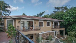 Ein zweistöckiges Haus mit Balkon, Steinhausfassade und Garten.
