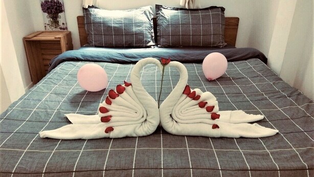 A bed with a checkered bedspread and two swan-shaped pillows.