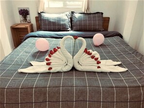 A bed with a checkered bedspread and two swan-shaped pillows. - H Best Hostel Cafe Saigon (Ho Chi Minh City)