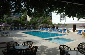 Una piscina al aire libre de temporada, sombrillas, tumbonas