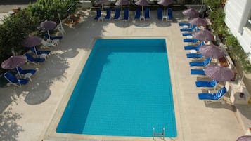 Una piscina al aire libre de temporada, sombrillas, tumbonas