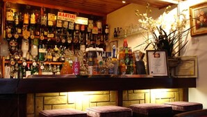 A bar area with stools, a variety of liquor bottles, and a sign for Martini. - Candlesticks (Stamford)