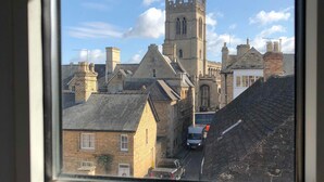 A view of a historic church with a tall tower and a paved area in front. - Candlesticks (Stamford)