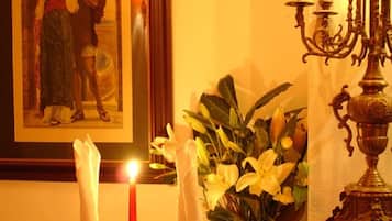 A framed painting of a couple, a lit candle, and a vase with yellow flowers.