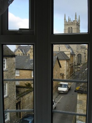 A view from a window overlooking a street with historic buildings and a church tower.