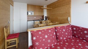 A compact living space with a kitchenette, a dining area, and a sofa with a red snowflake pattern.
