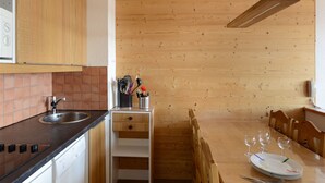 A kitchen with wooden cabinets, a black countertop, a sink, and a dining area with a table set for four.