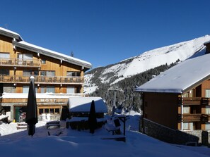 A wooden building with balconies, surrounded by snow-covered mountains.