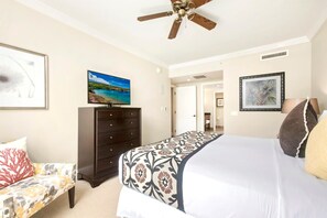 A bedroom with a bed, a dresser, a ceiling fan, and a TV on the wall.
