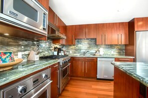 A modern kitchen with wooden cabinets, stainless steel appliances, and a granite countertop.