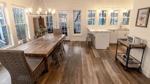 A spacious kitchen with a wooden dining table, wicker chairs, and a hanging light fixture. - Resort Home near Lake Michigan with Golf Cart (Michigan City)