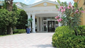 A building entrance with a tiled pathway, columns, and a door with signage. - Hierapolis Termal Hotel (Denizli)