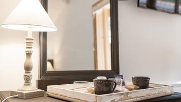 A bedside table with a lamp, a tray with a cup, a small bowl, and a decorative item.