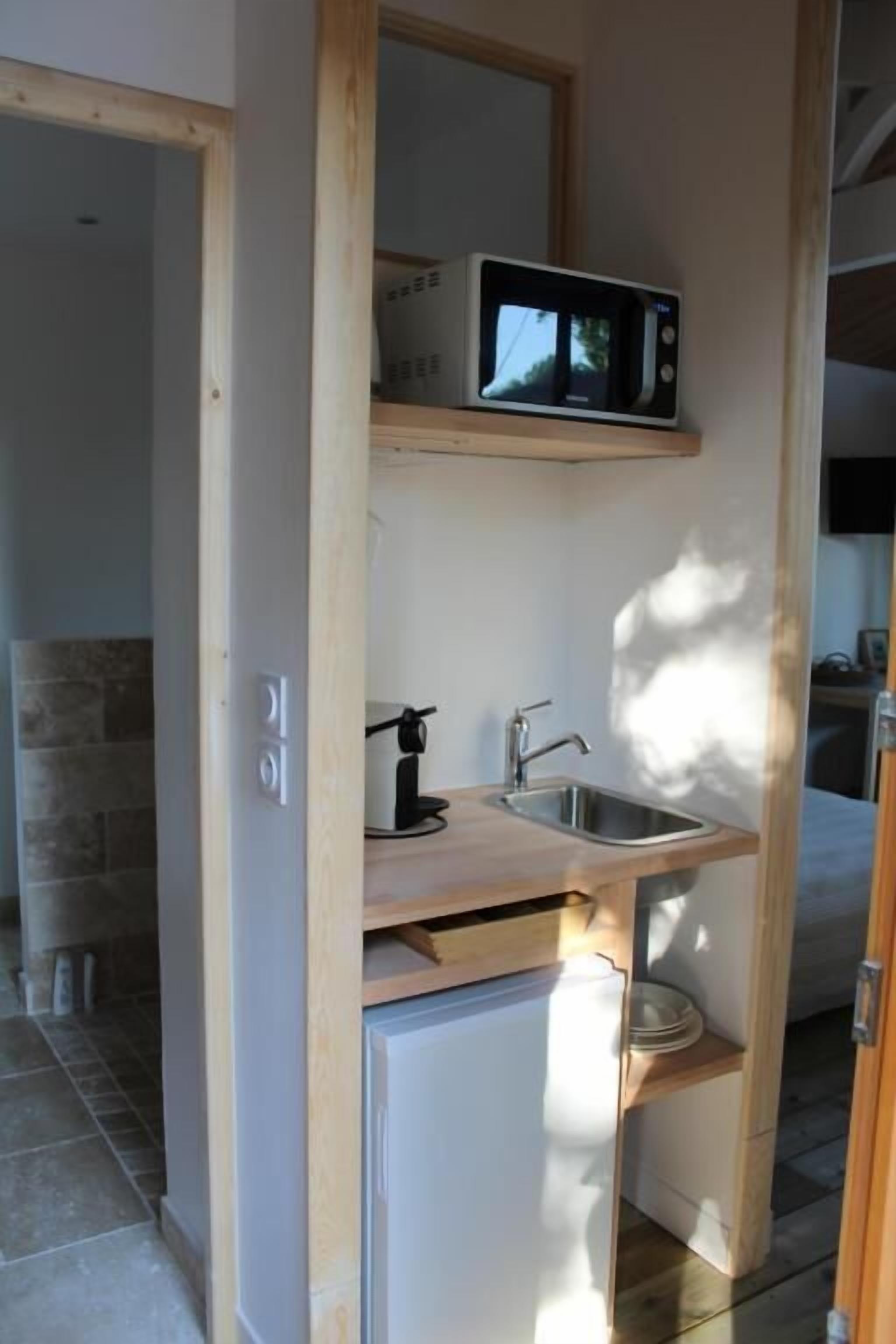 A compact kitchen with a microwave, sink, and small refrigerator.