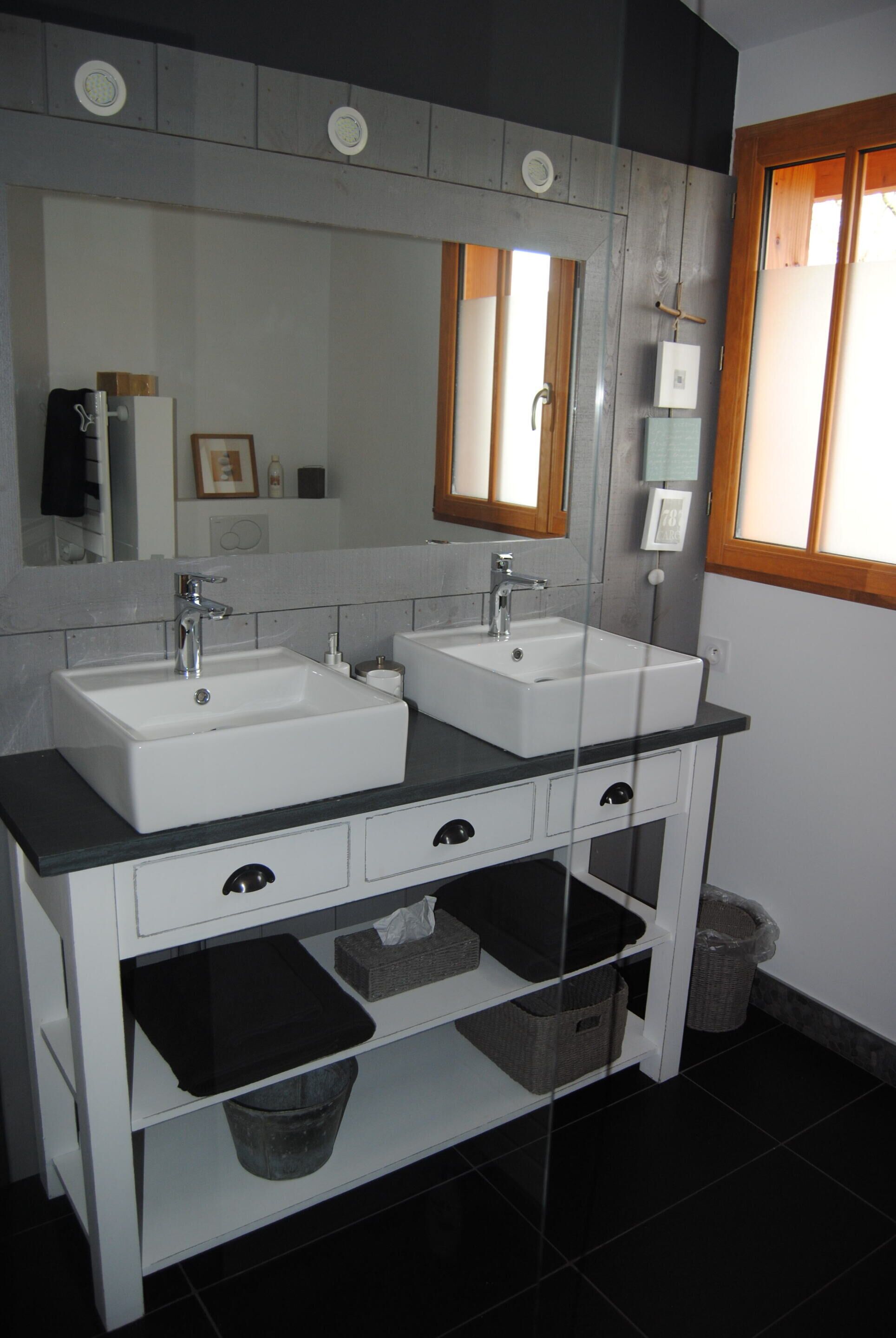 Une salle de bain avec deux lavabos, un grand miroir et une fenêtre.