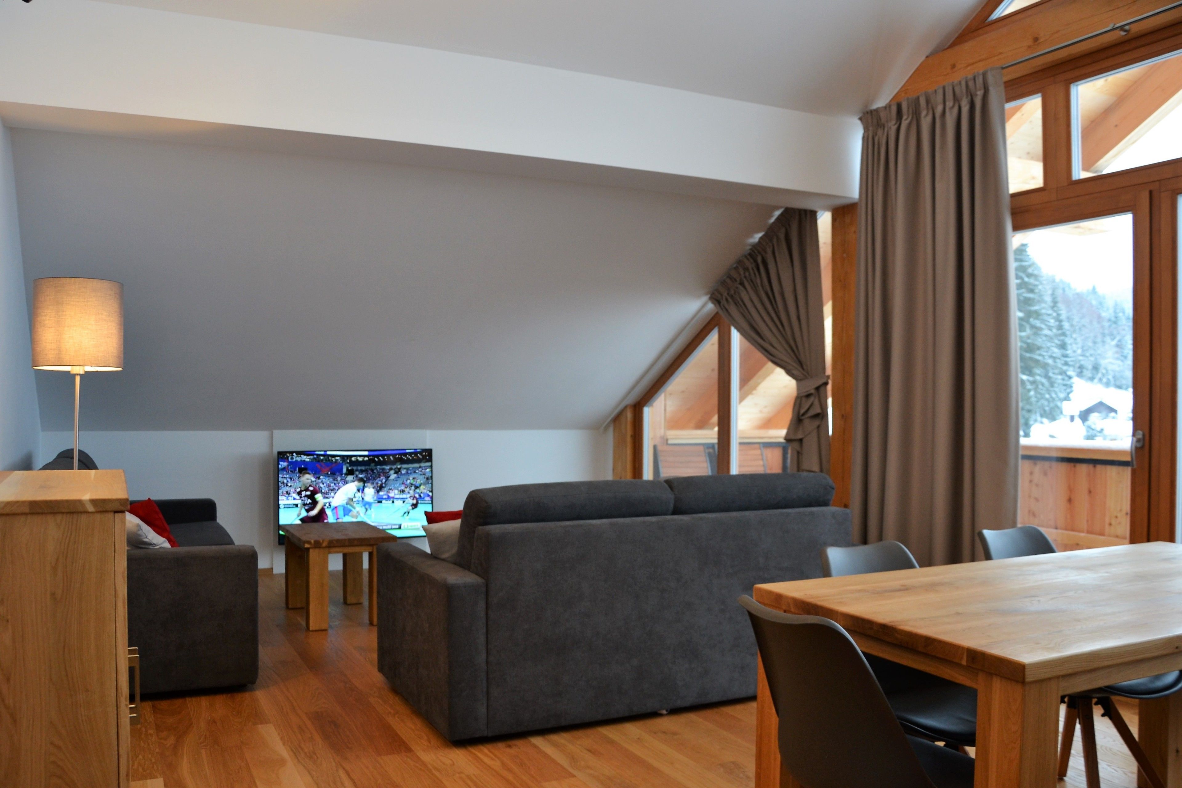 Una sala moderna con sofá, televisor y mesa de comedor de madera.