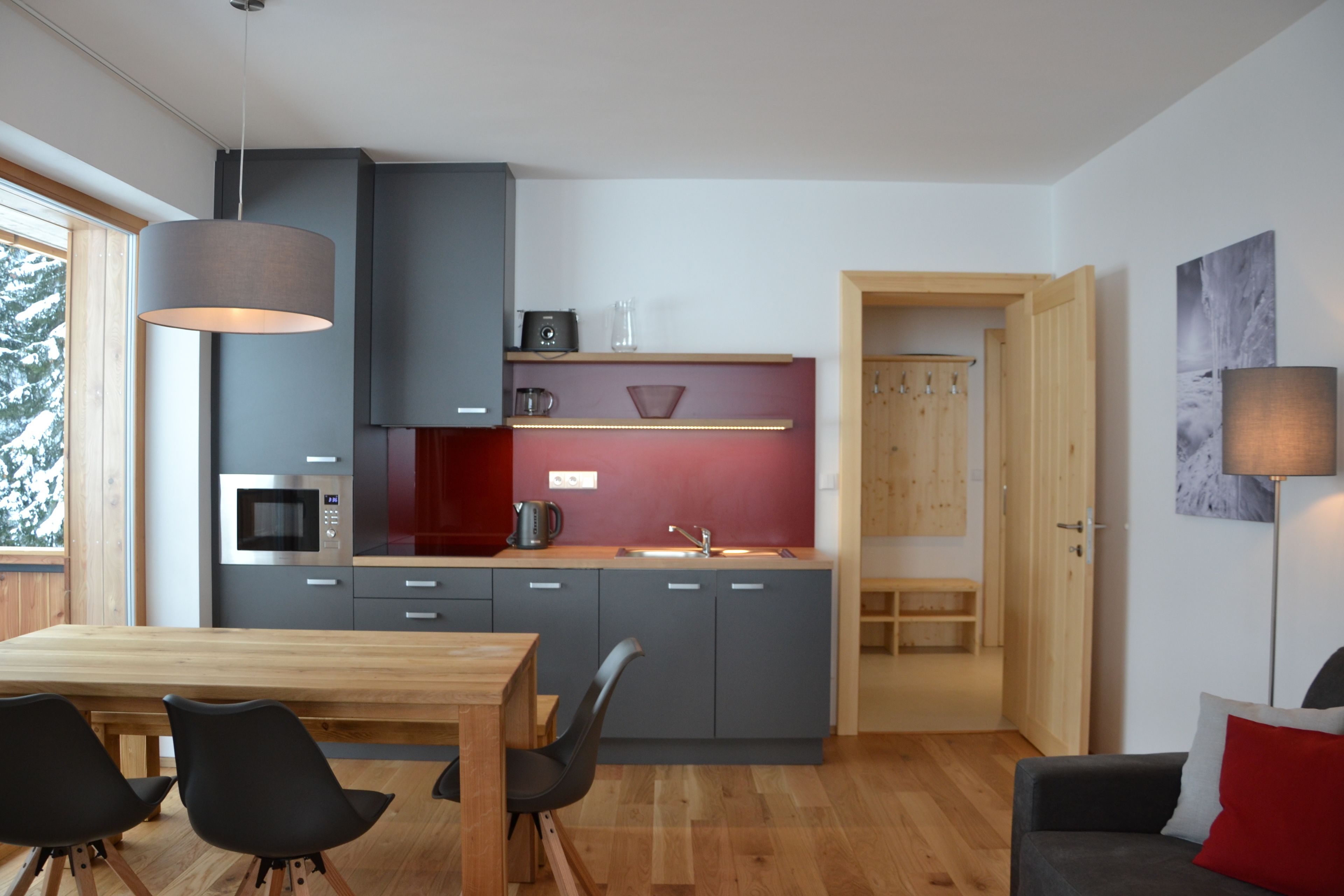 A modern kitchen with grey cabinets, a wooden dining table, and black chairs.