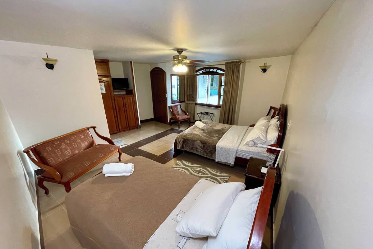 Ein Hotelzimmer mit einem Bett, einer Sitzbank, einem Schreibtisch und einem Fernseher.