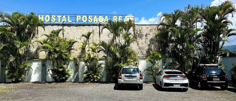 A building with a sign reading "HOSTAL POSADA REAL". There are three cars parked in front.