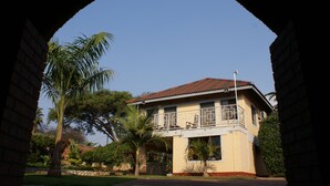 A two-story building with a balcony, surrounded by palm trees and a stone wall. - Premier Guest Lodge (Harare)
