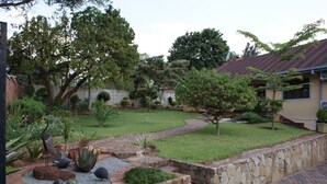 A well-maintained garden with a stone pathway, various plants, and a lawn. - Premier Guest Lodge (Harare)