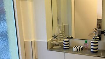 A bathroom with a white sink, a mirror, and a window.