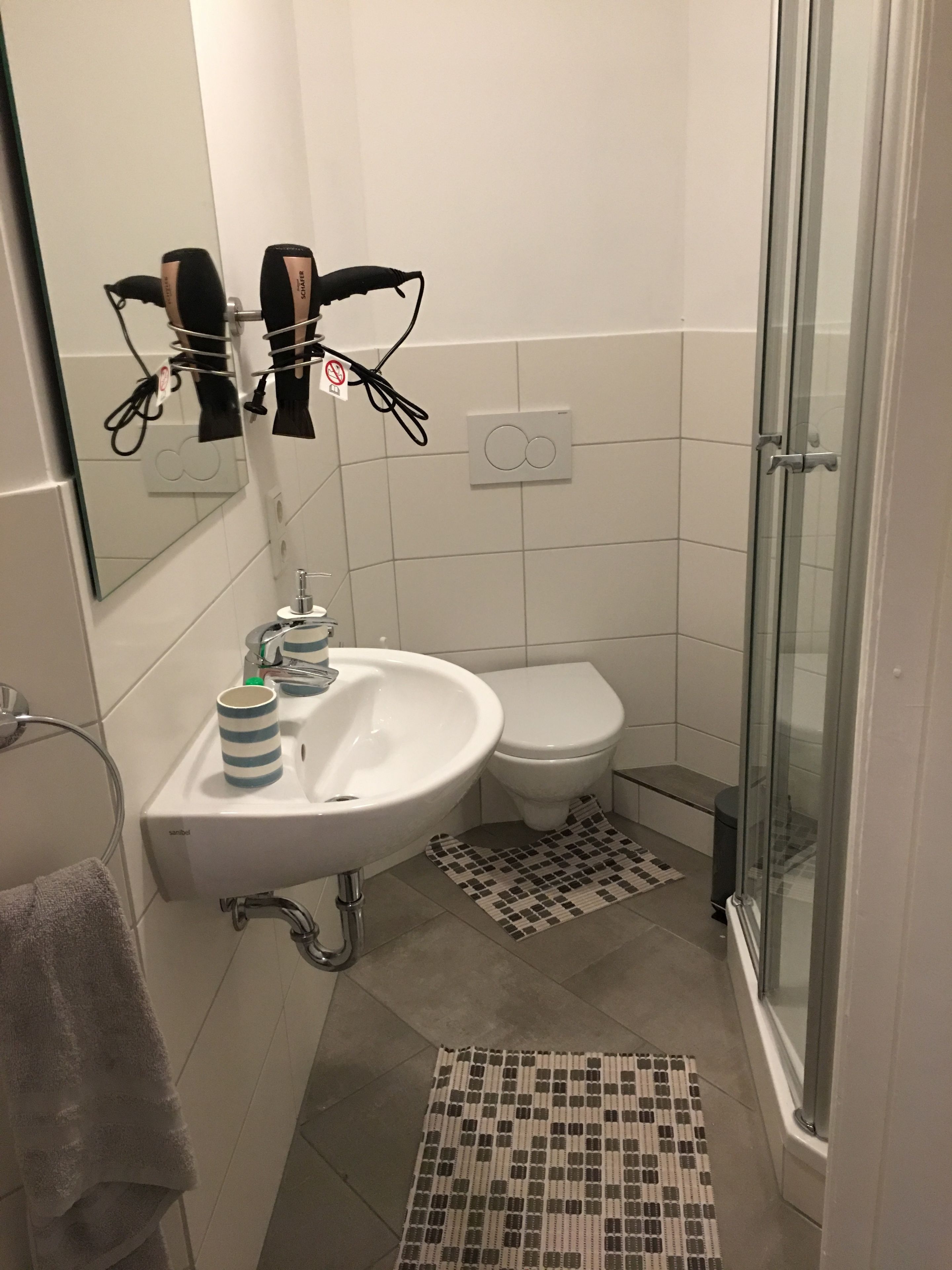 Une salle de bain avec un lavabo blanc, des toilettes, une douche et un porte-serviettes.