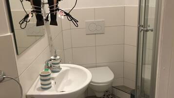 Une salle de bain avec un lavabo blanc, des toilettes, une douche et un porte-serviettes.