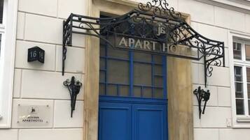 A building entrance with a blue door, a sign reading "APART HOTEL," and a number "16 16" on the wall.