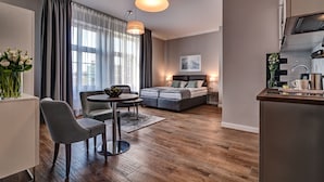 Een moderne hotelkamer met een zithoek, een bank en een kitchenette.