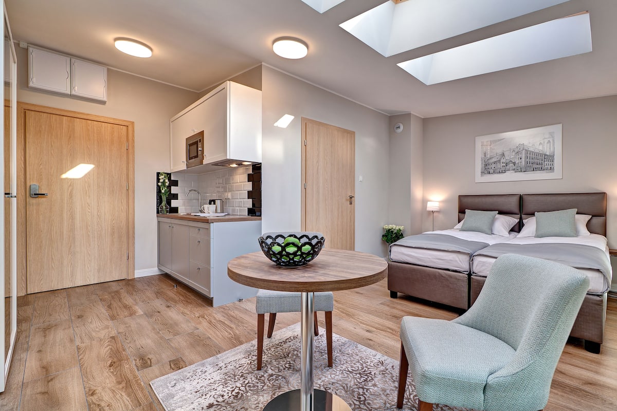 Een moderne slaapkamer met een groot bed, een eettafel met een schaal en een keukenhoek.