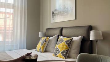 A hotel room with a bed, a bedside table with a book, a lamp, and a painting on the wall.