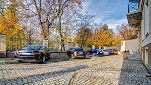 Een keienpad dat leidt naar een toegangspoort met geparkeerde auto's.