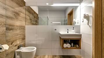 Une salle de bain moderne équipée d’un bidet, d’un lavabo et d’un meuble-lavabo en bois.
