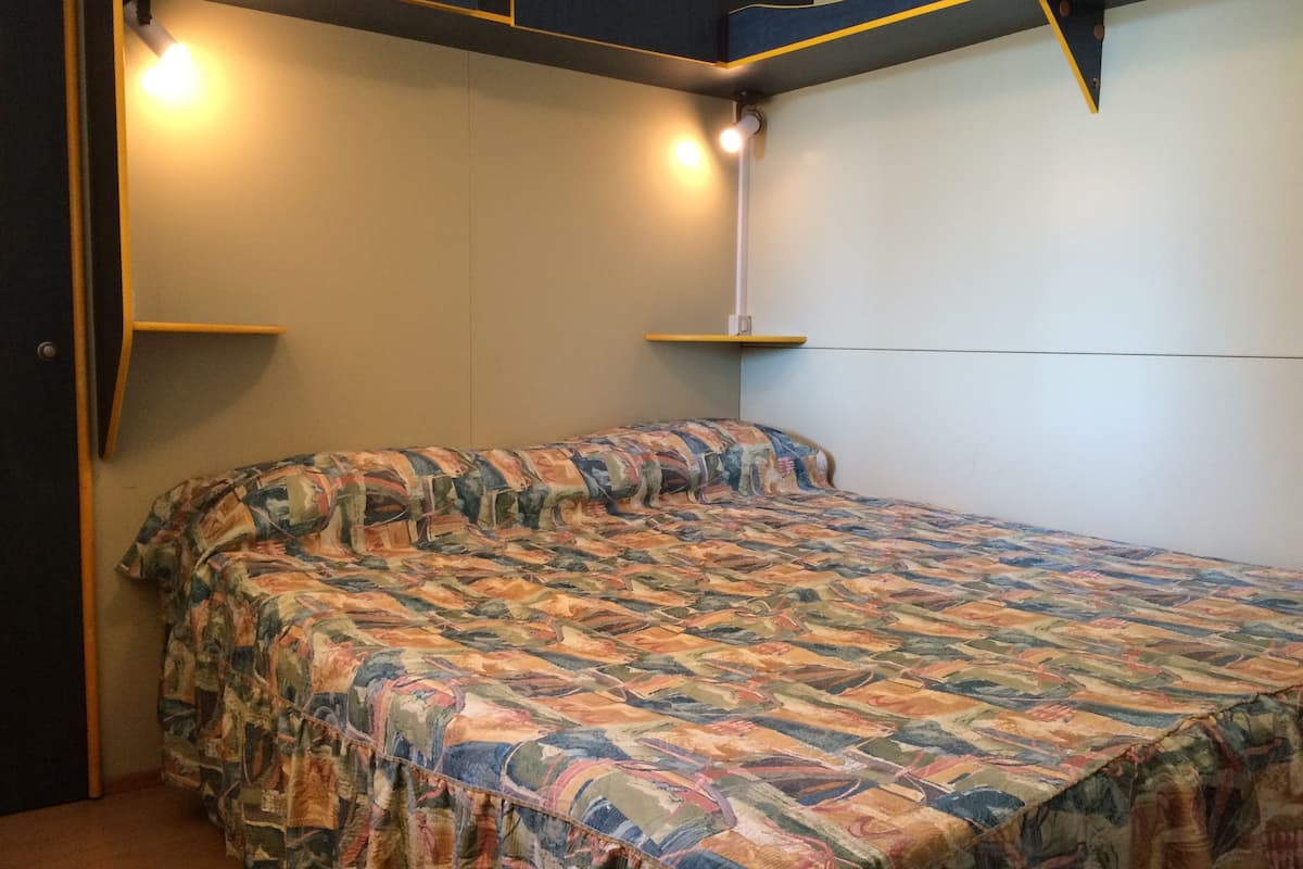 Une chambre à coucher avec un lit, deux tables de chevet et une étagère fixée au mur.