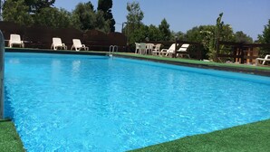 A swimming pool with clear blue water, surrounded by white lounge chairs and a wooden fence. - Camping Valle Dei Templi (Agrigento)