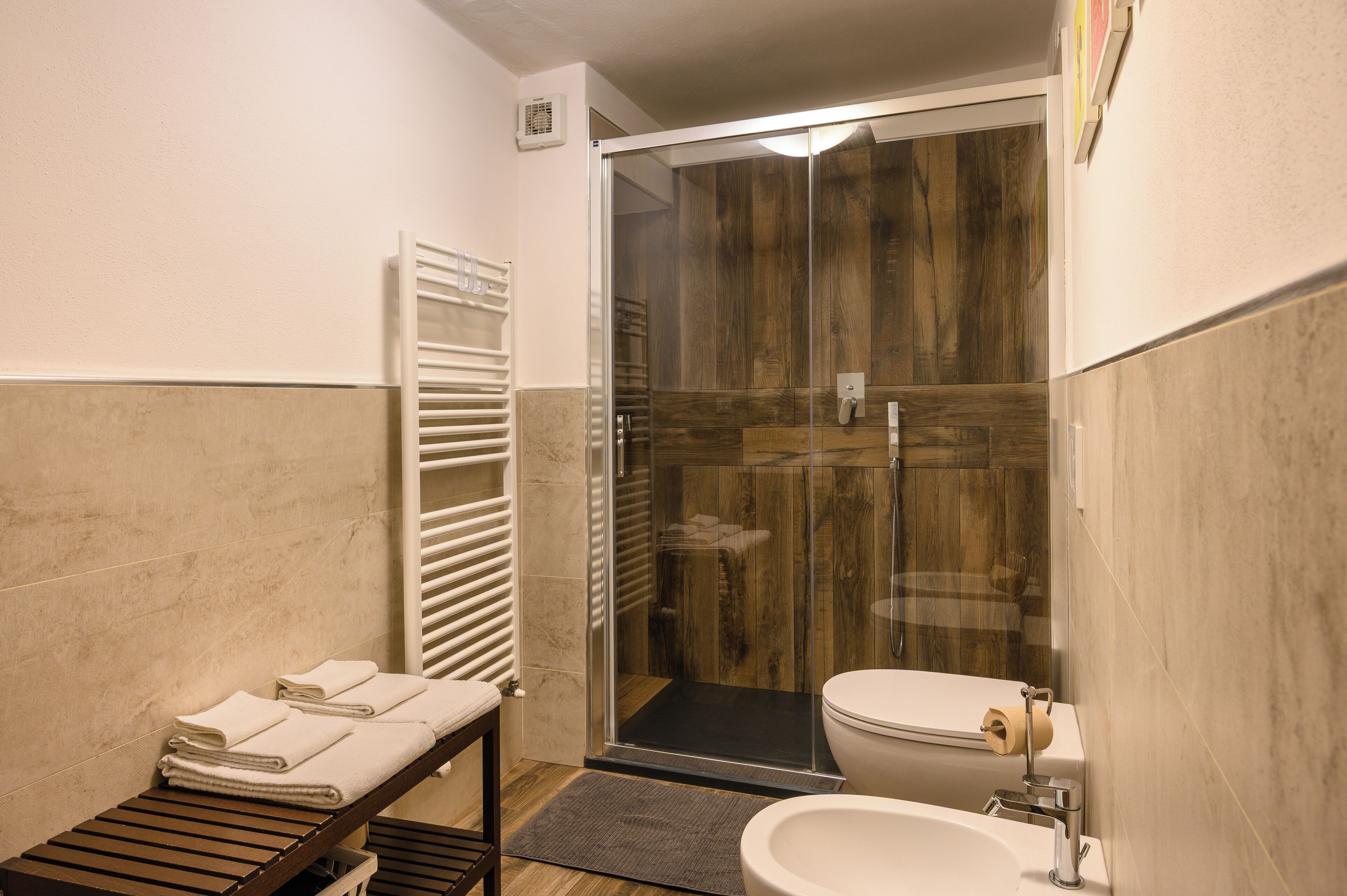 Un baño con ducha de mampara de vidrio, inodoro y lavamanos.