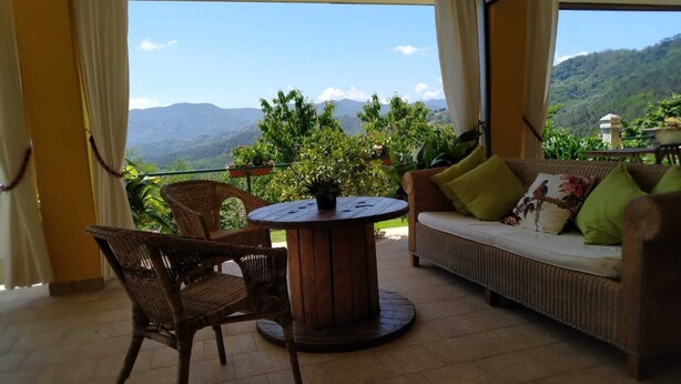 A balcony with wicker furniture, a round table, and a sofa with cushions. - Il Murice B&B (Vezzano Ligure)
