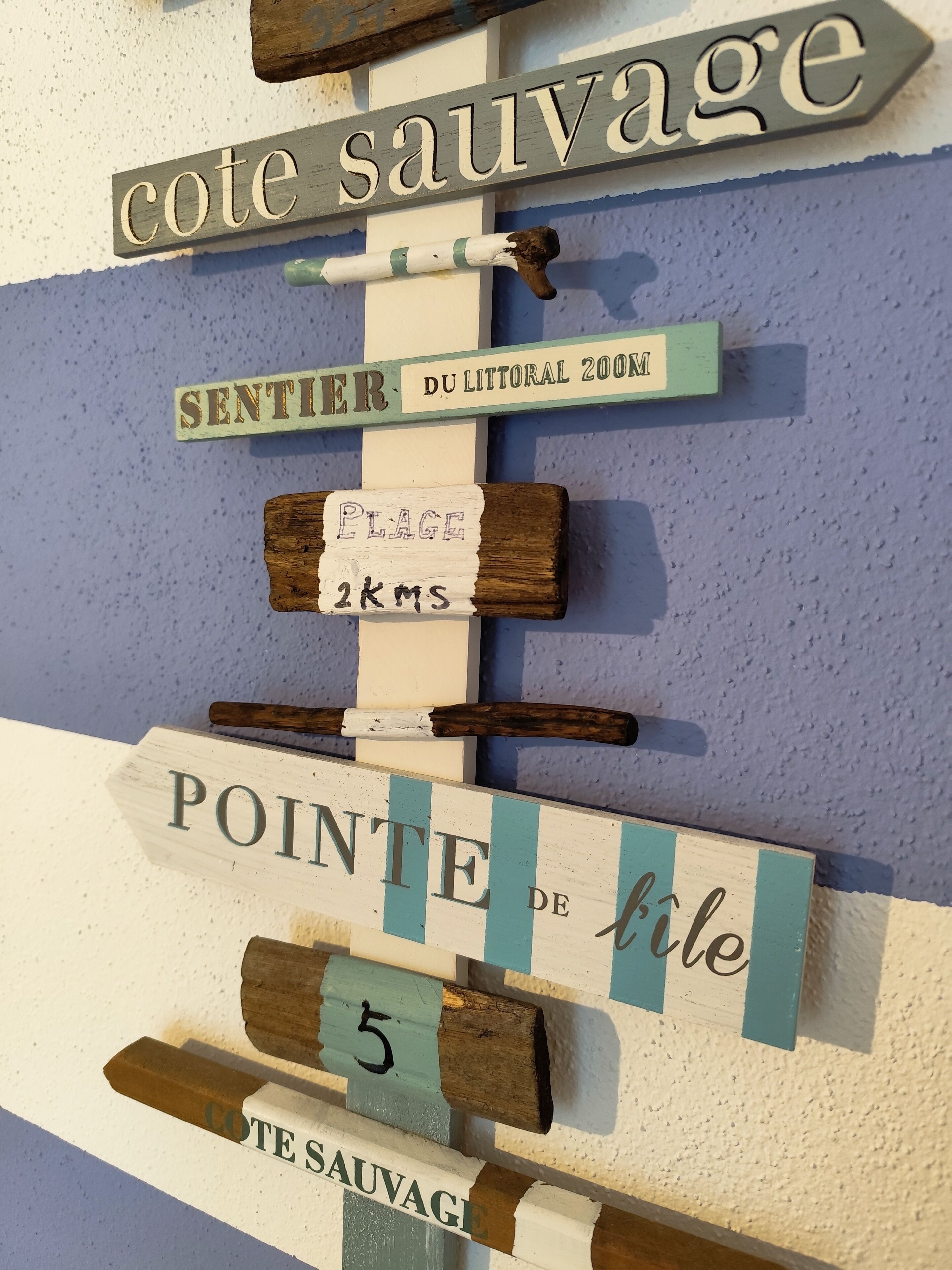A wall with various signs, including 'cote sauvage' and 'sentier du littoral 200m'.