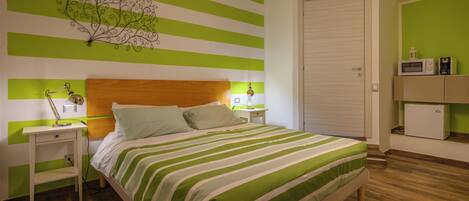Un dormitorio con cama, mesitas de noche, cómoda y pared con rayas verdes.
