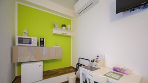 A compact kitchenette with a microwave, coffee maker, and mini-fridge. A small trash bin is near the sink, and a chair is positioned at a white table with a small desk. - Il Murice B&B (Vezzano Ligure)